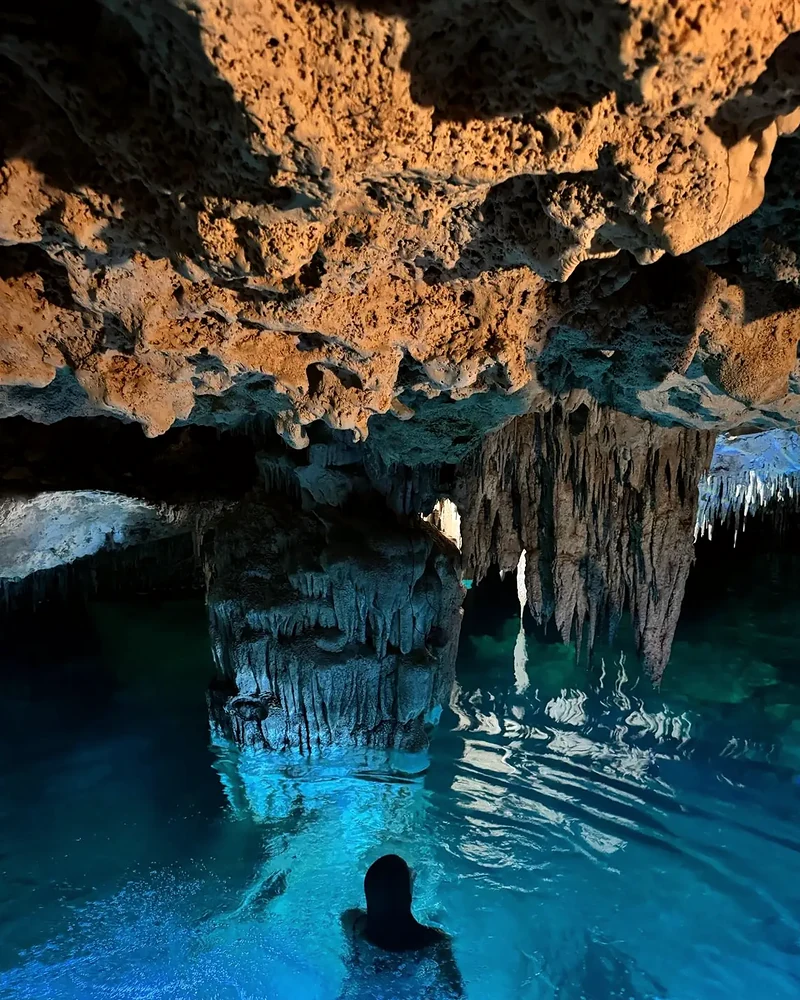 Una persona nada en un cenote bajo estalactitas, en Selvadentro